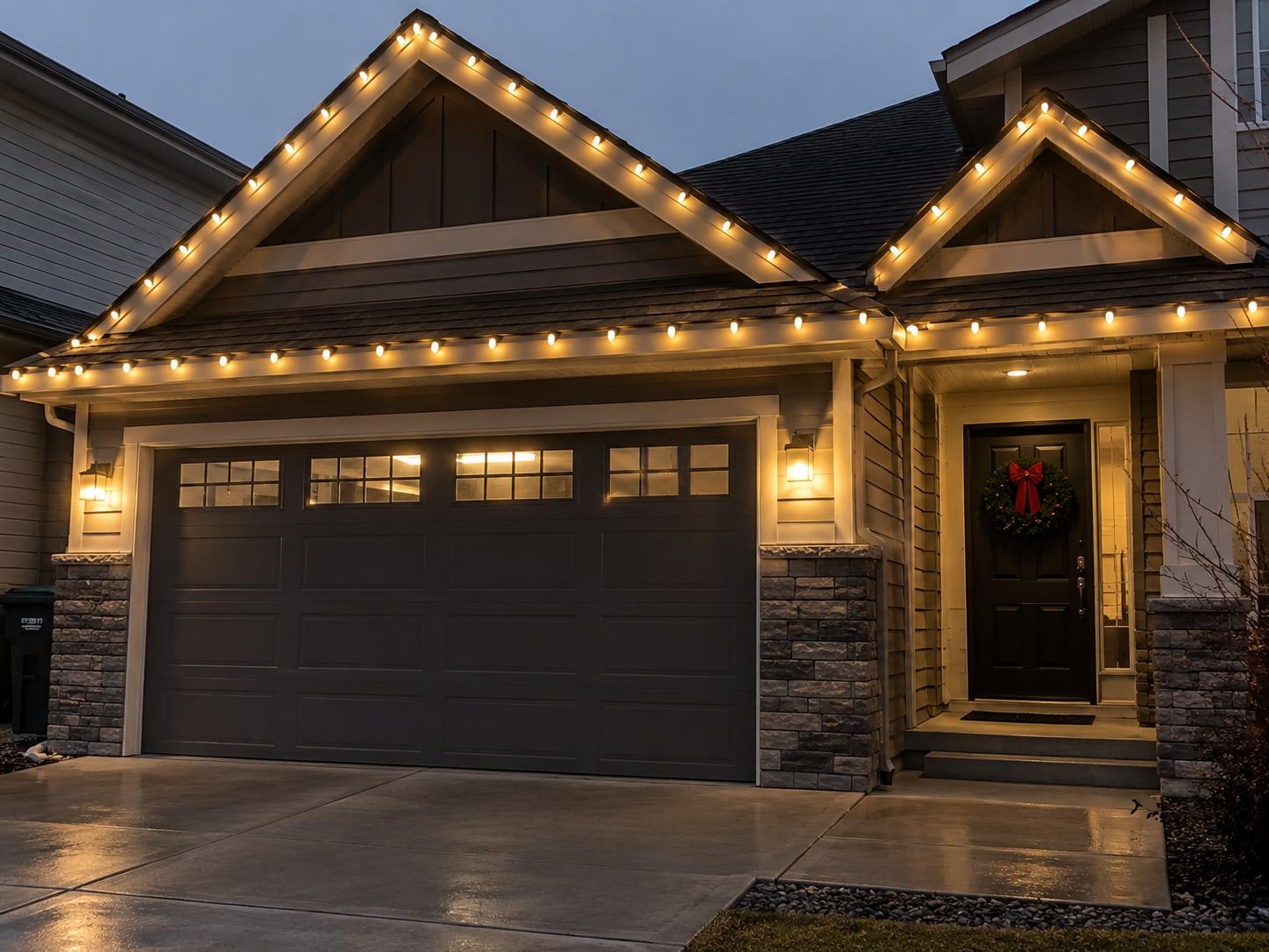 Home with warm white C9 lights along the rooflines and a wreath on the front door
